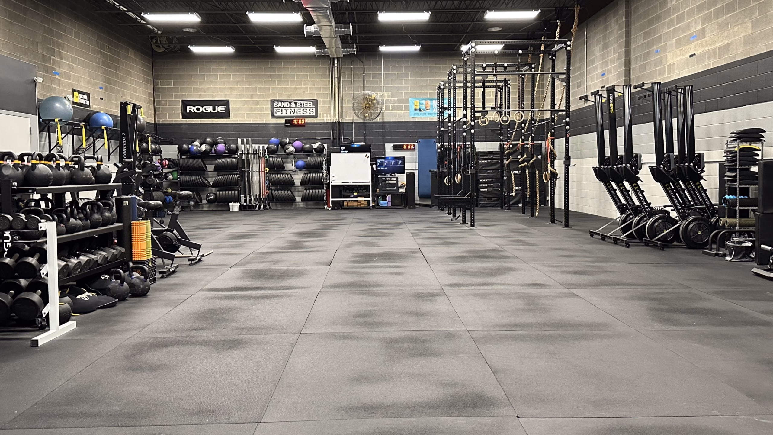 Open Gym at Sand & Steel Fitness in Alexandria VA — open floor, Rogue racks, kettlebells, bumper plates, and Sand & Steel signage