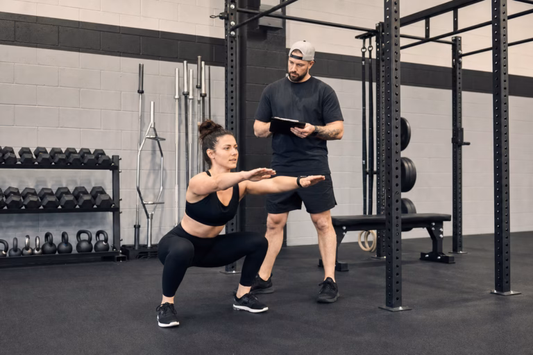 Coach assessing a client's squat during a personal training movement assessment at Sand & Steel Fitness in Alexandria VA