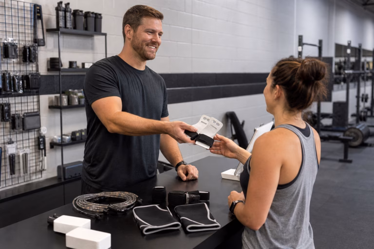 Coach helping a member choose grips at the Sand & Steel Fitness pro shop